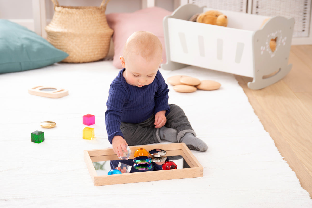 Small wooden mirror tray with mirrored insert and assorted colorful toy pieces