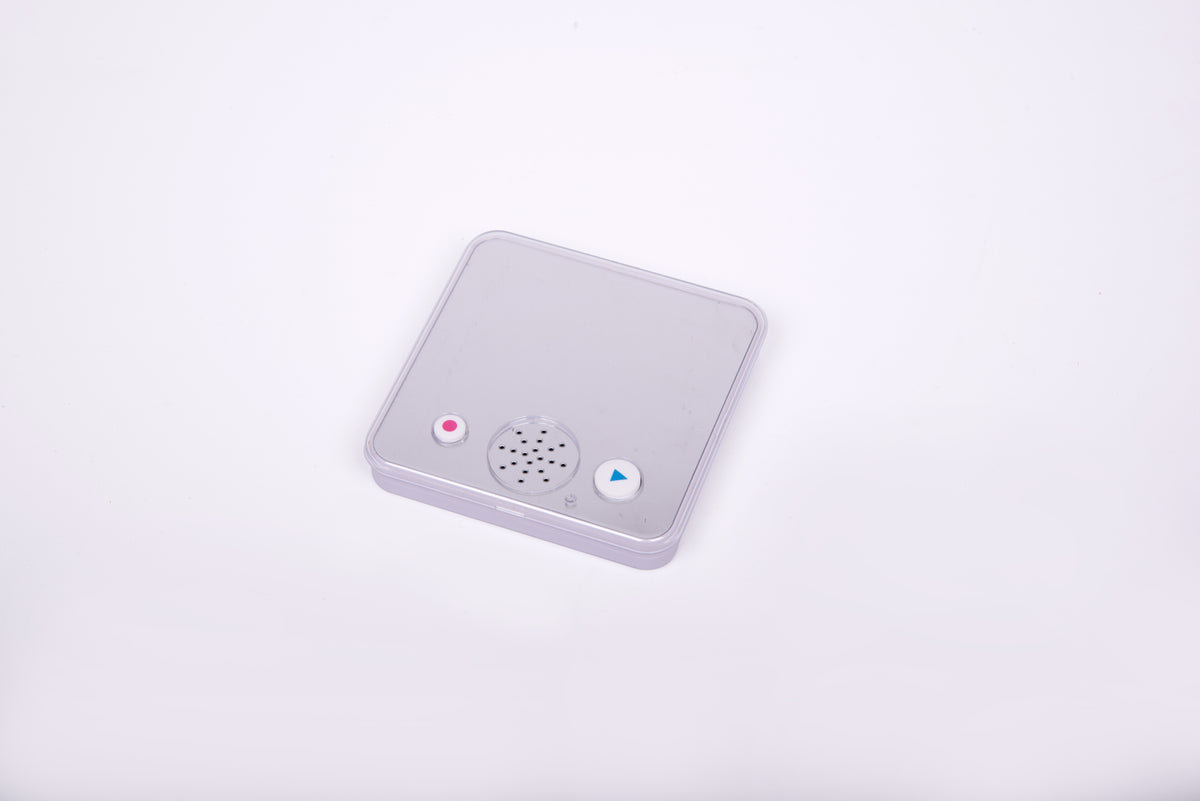 Small gray sound-and-mirror device with speaker grille, lights, and play button