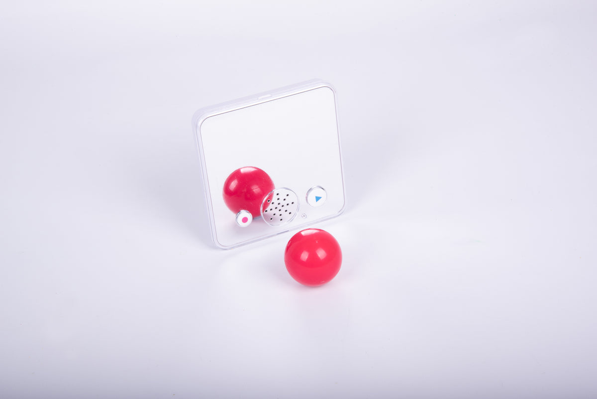 Clear-front sound-and-mirror device with red ball accessory and speaker grille