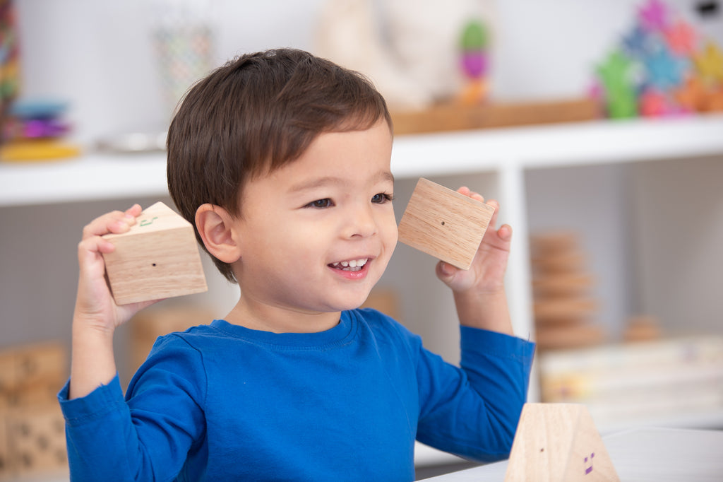 Child holding wooden sound prism blocks with colorful musical note decals