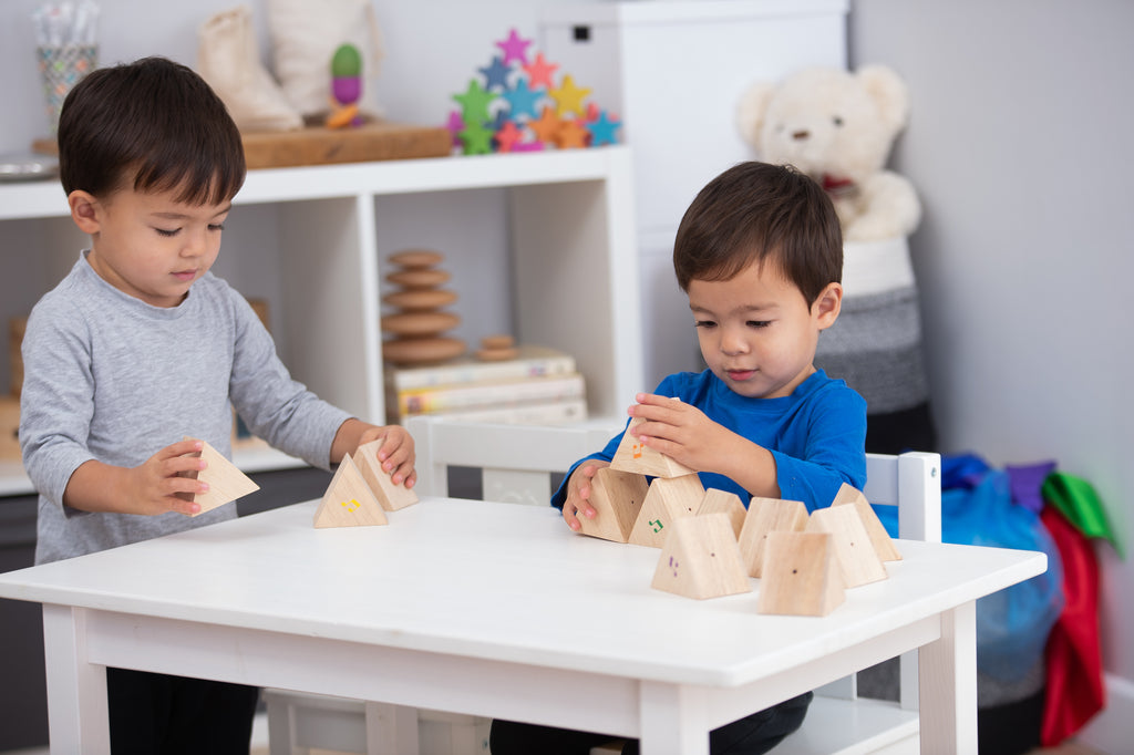 Wooden sound prism blocks on table with musical note decals as child stacks pieces