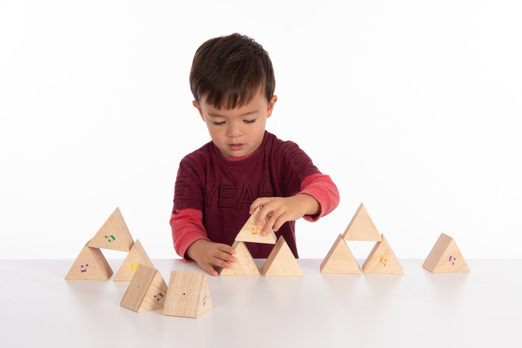 Wooden sound prism blocks set with musical note decals, child playing at table