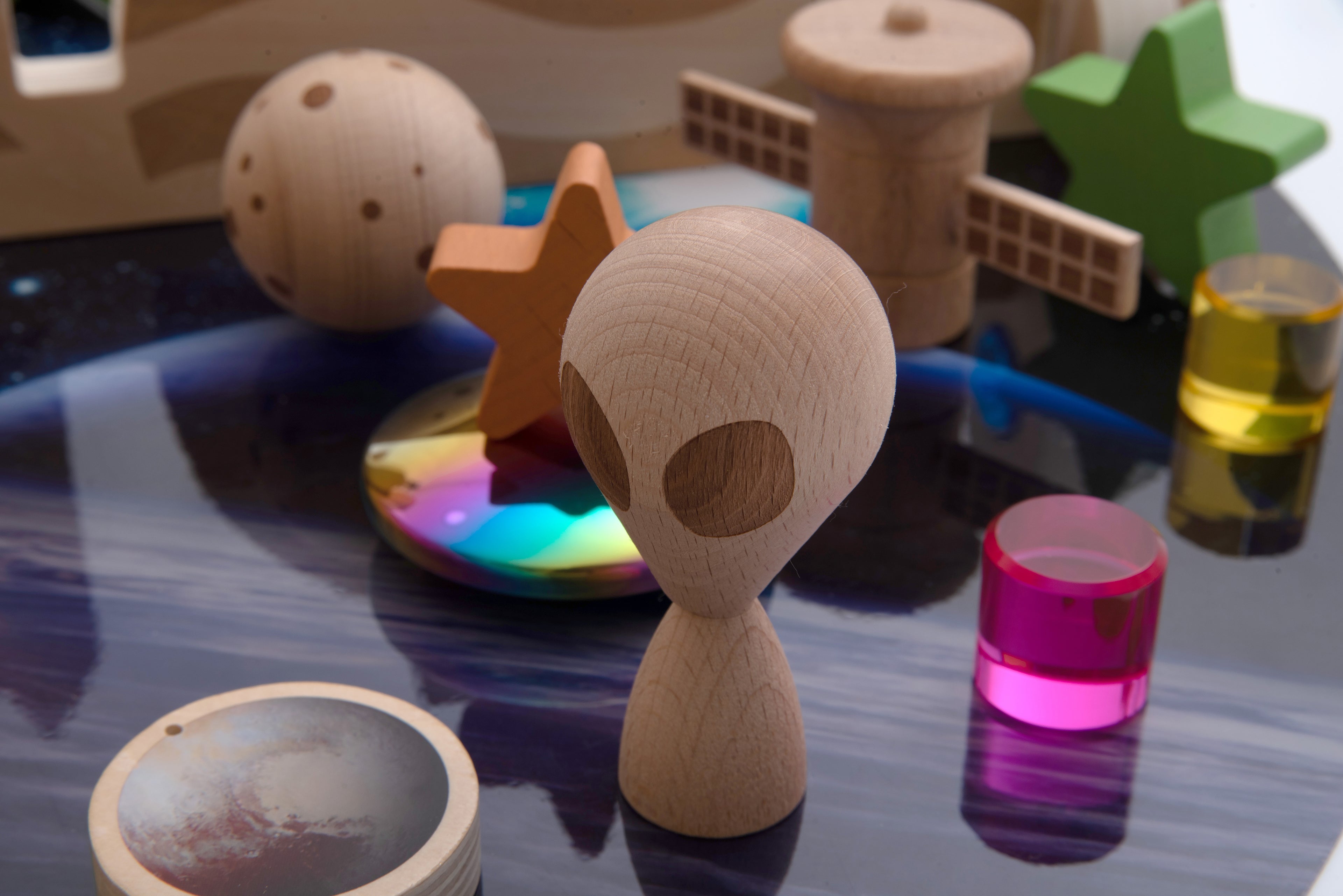 Wooden astronaut-style figurine with small wooden space pieces and colored glass cylinders