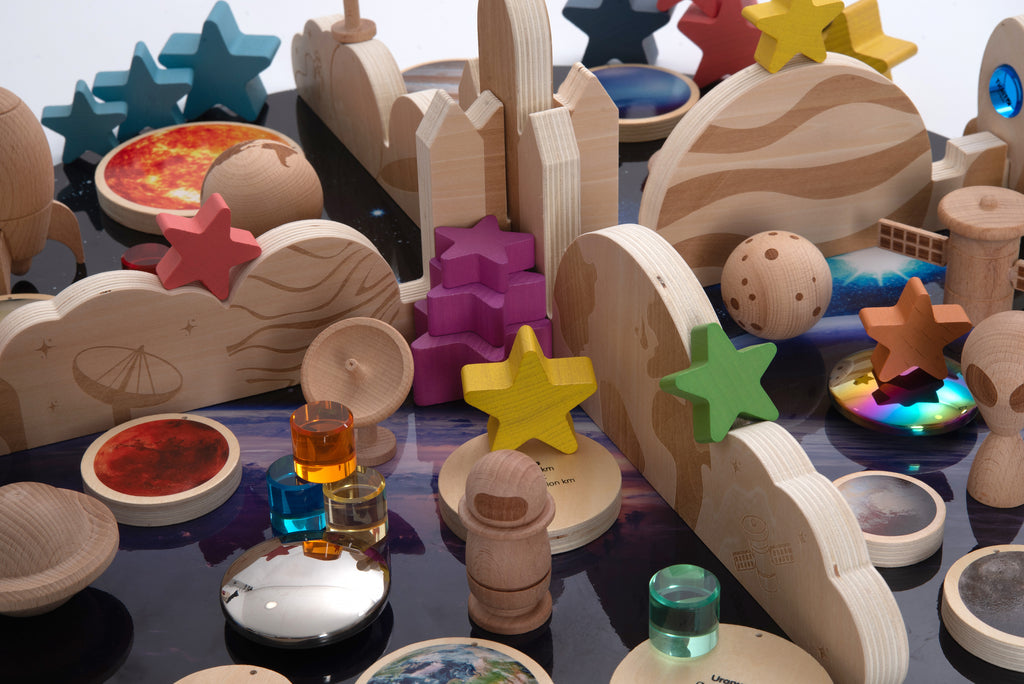 Wooden space-themed pieces with colorful star shapes, rockets, and planet discs