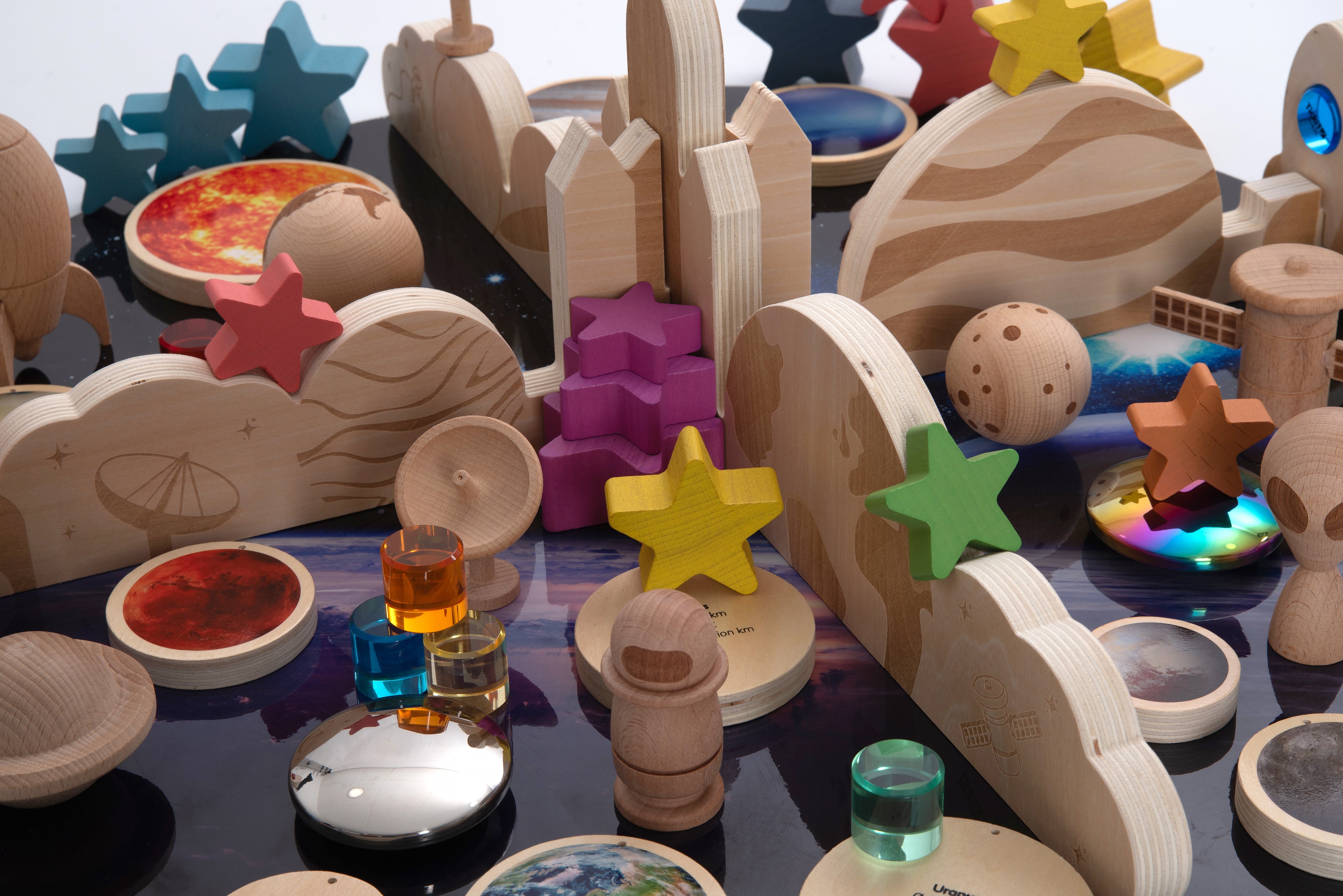 Wooden space-themed pieces with colorful star shapes, rockets, and planet discs