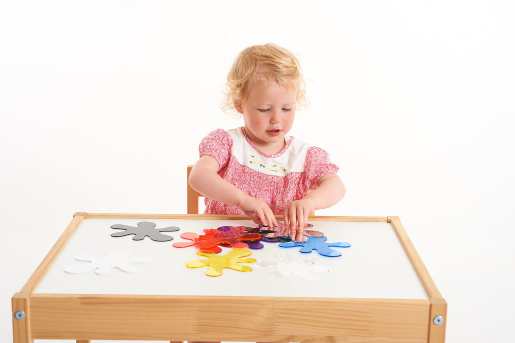 Child arranging colorful foam splash puzzle pieces on a wooden frame board