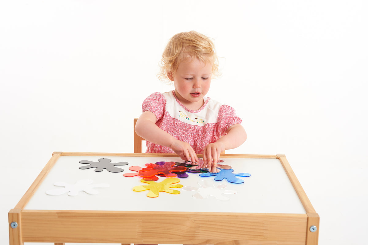 Child arranging colorful foam splash puzzle pieces on a wooden frame board