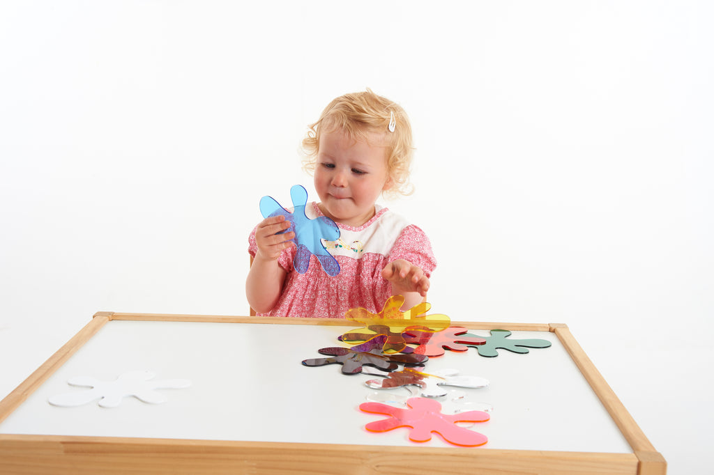 Toddler holding colorful foam puzzle pieces over a wooden frame board
