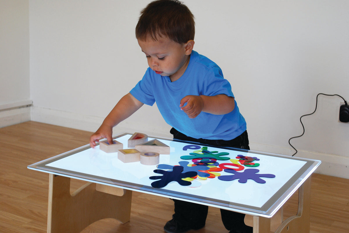 Child playing with colorful foam puzzle pieces on a white tabletop board