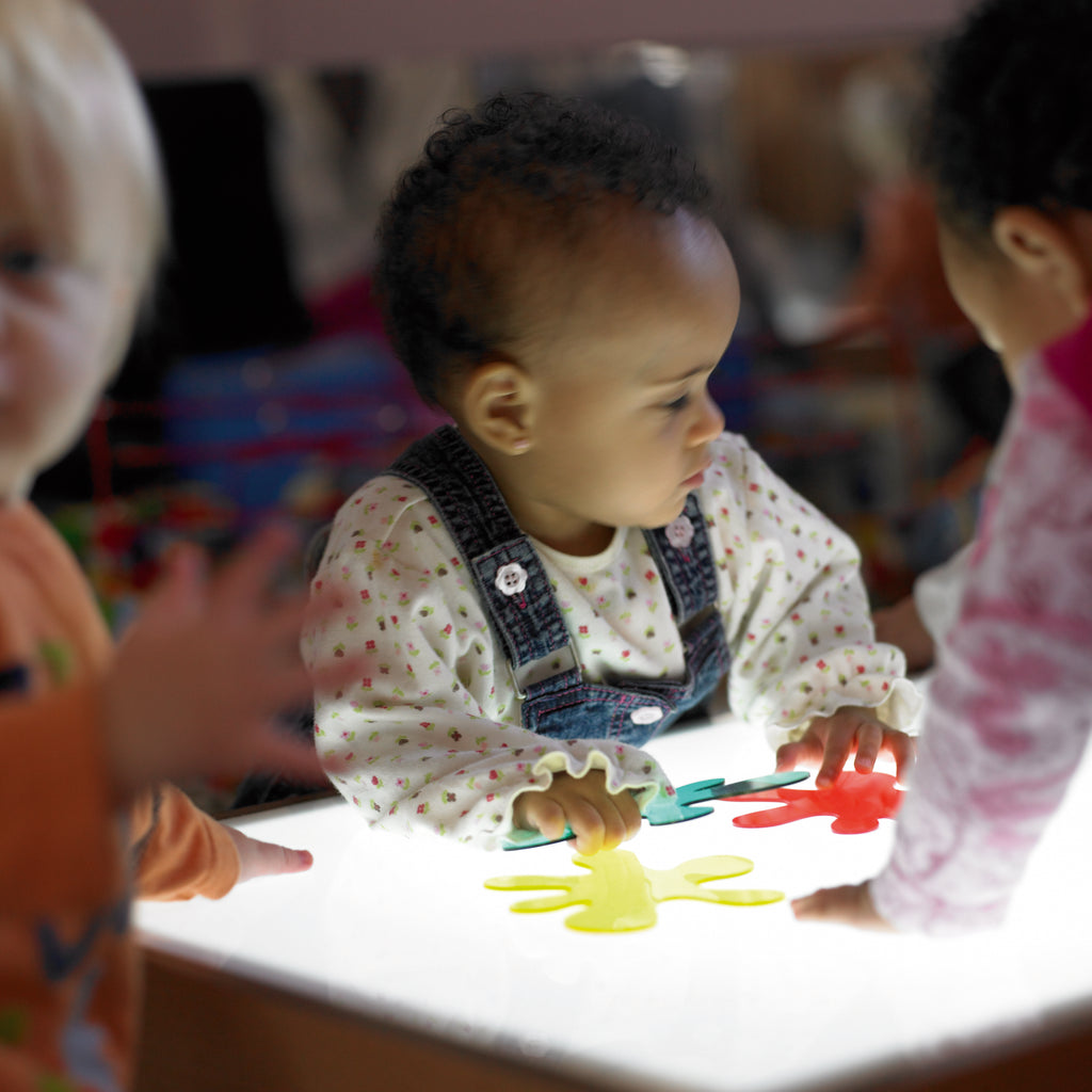 Kids playing with colorful foam puzzle pieces on a white activity table