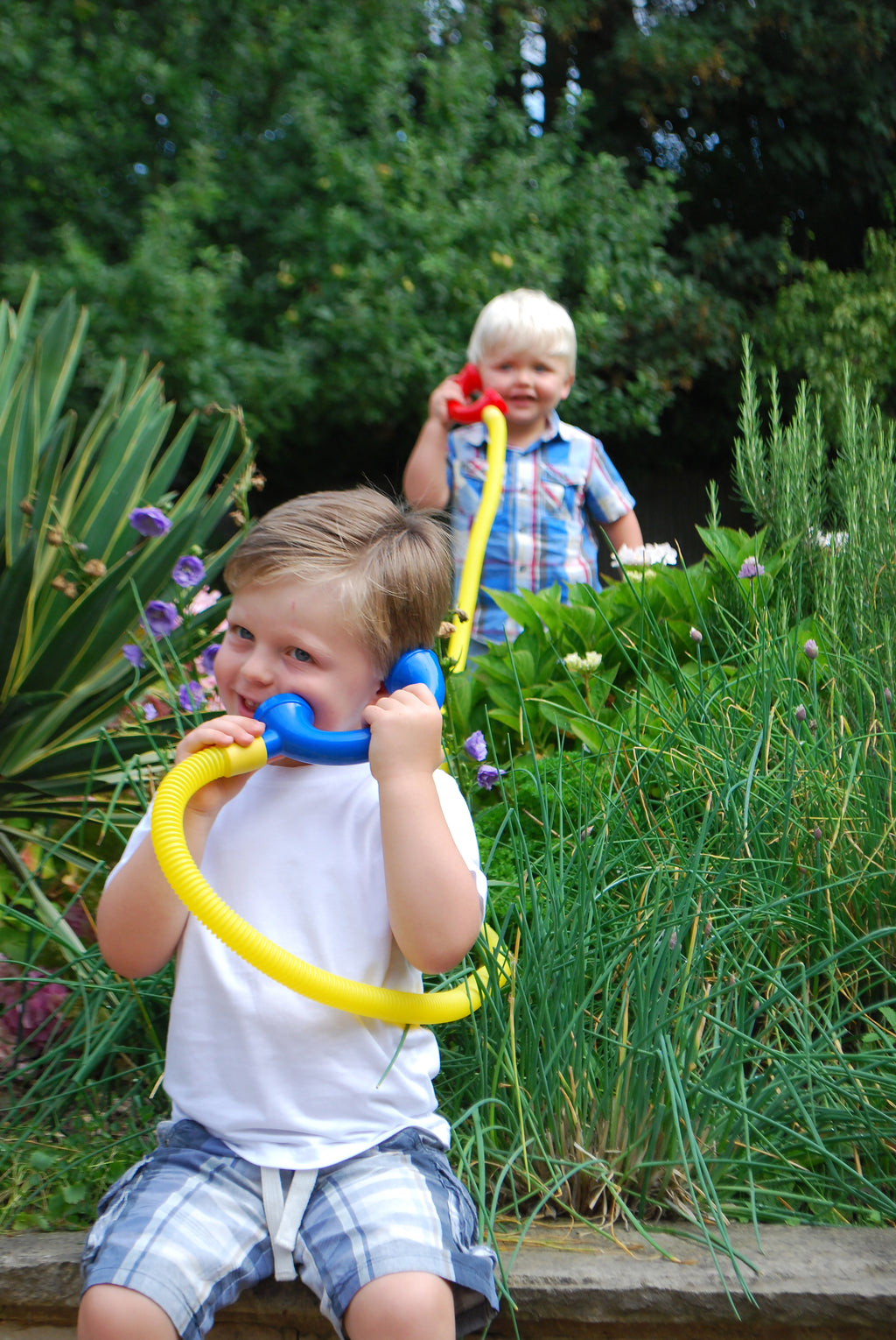 Child using a yellow talking tube with a blue mouthpiece end