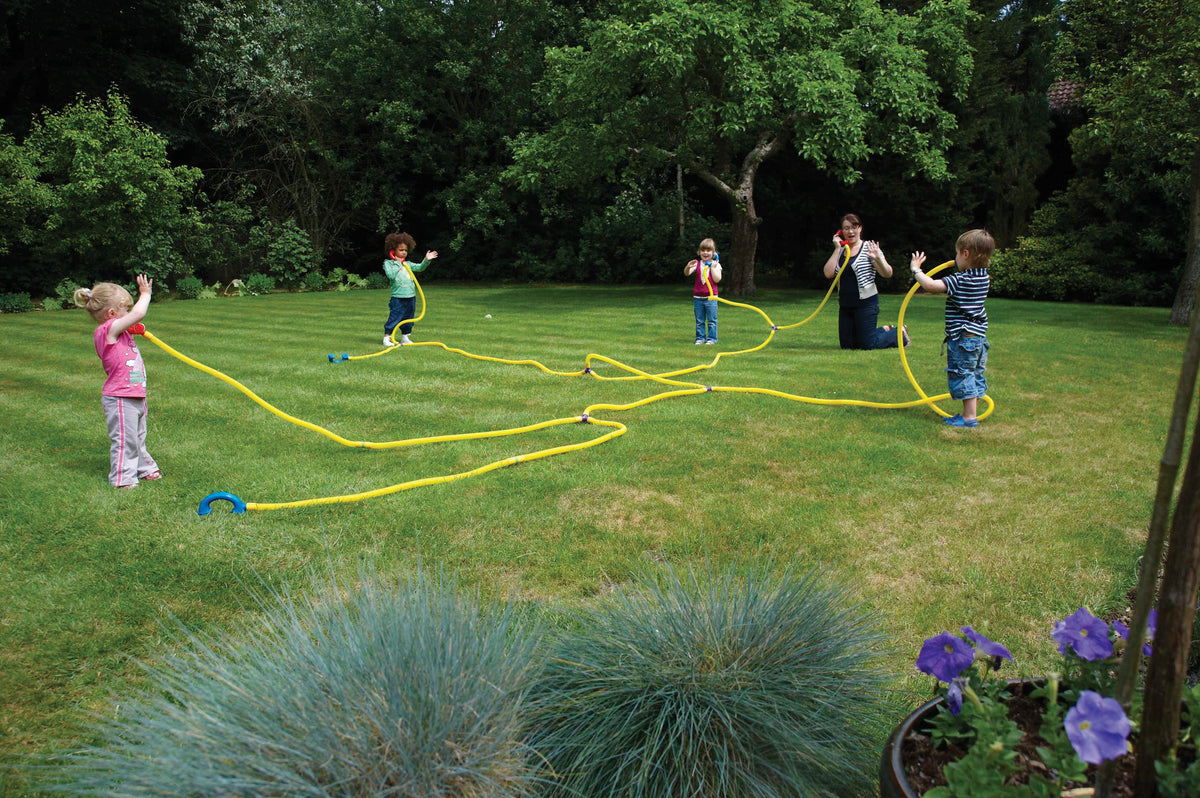 Yellow talking tube telephone exchange set with blue ear pieces on grass, children playing