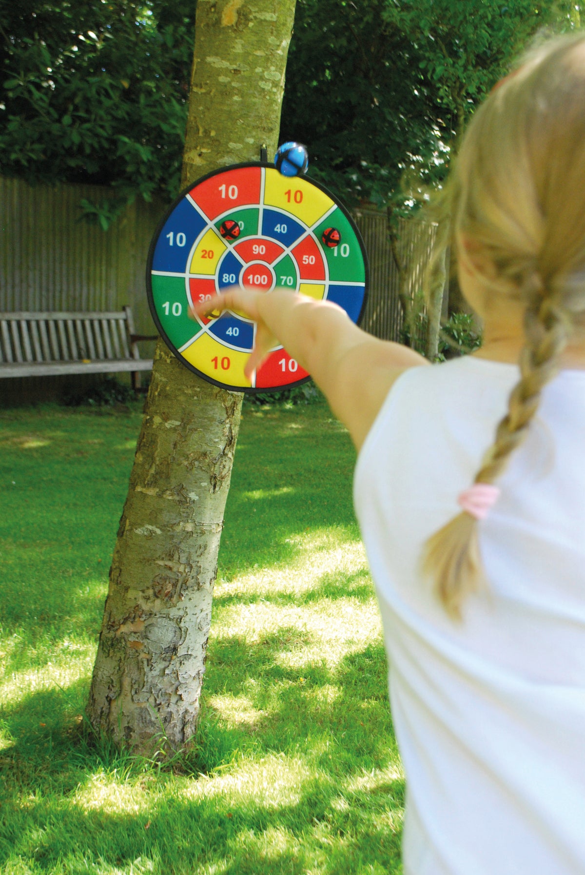 Kids target dartboard mounted on a tree with a pointing player’s arm