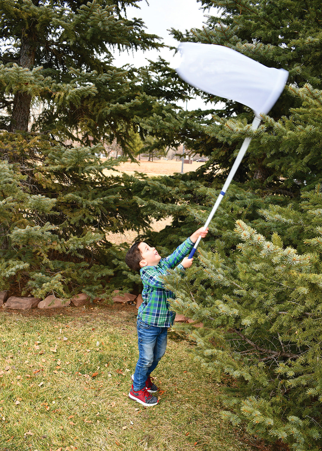 Telescopic sweep net with white mesh bag and long white handle, extended outdoors