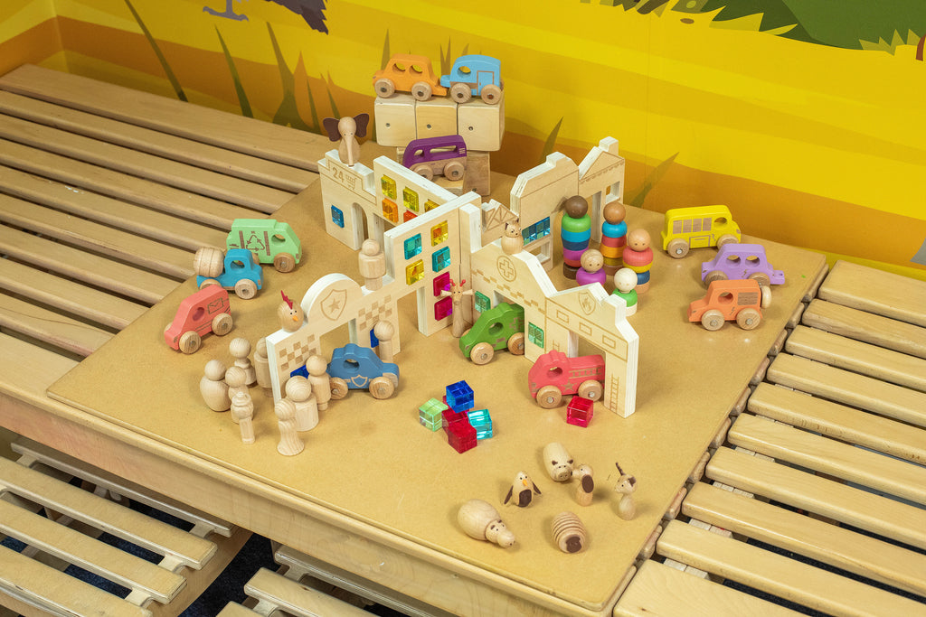 Wooden toy town set on track-style base with figures, cars, and buildings