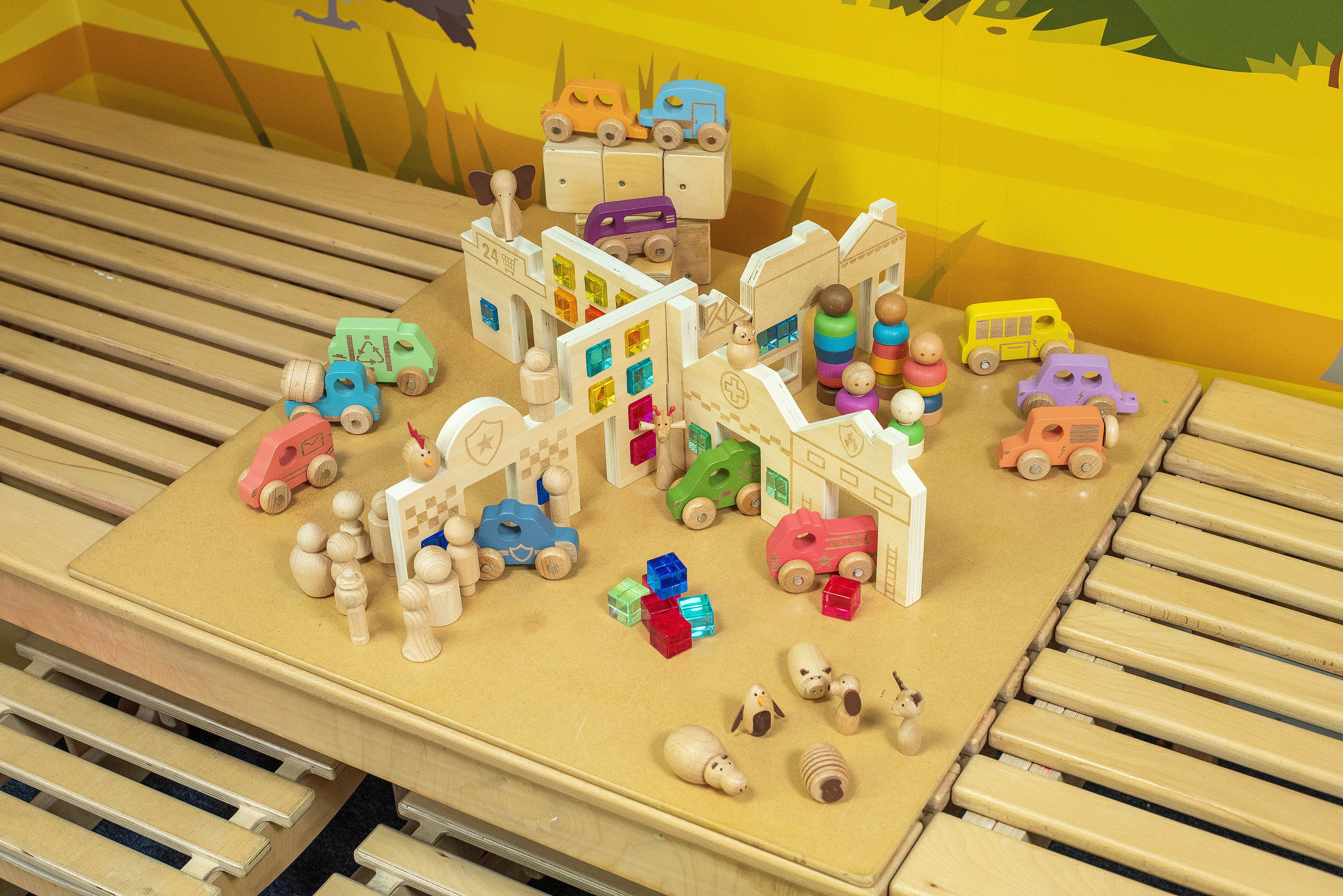 Wooden toy town set on track-style base with figures, cars, and buildings
