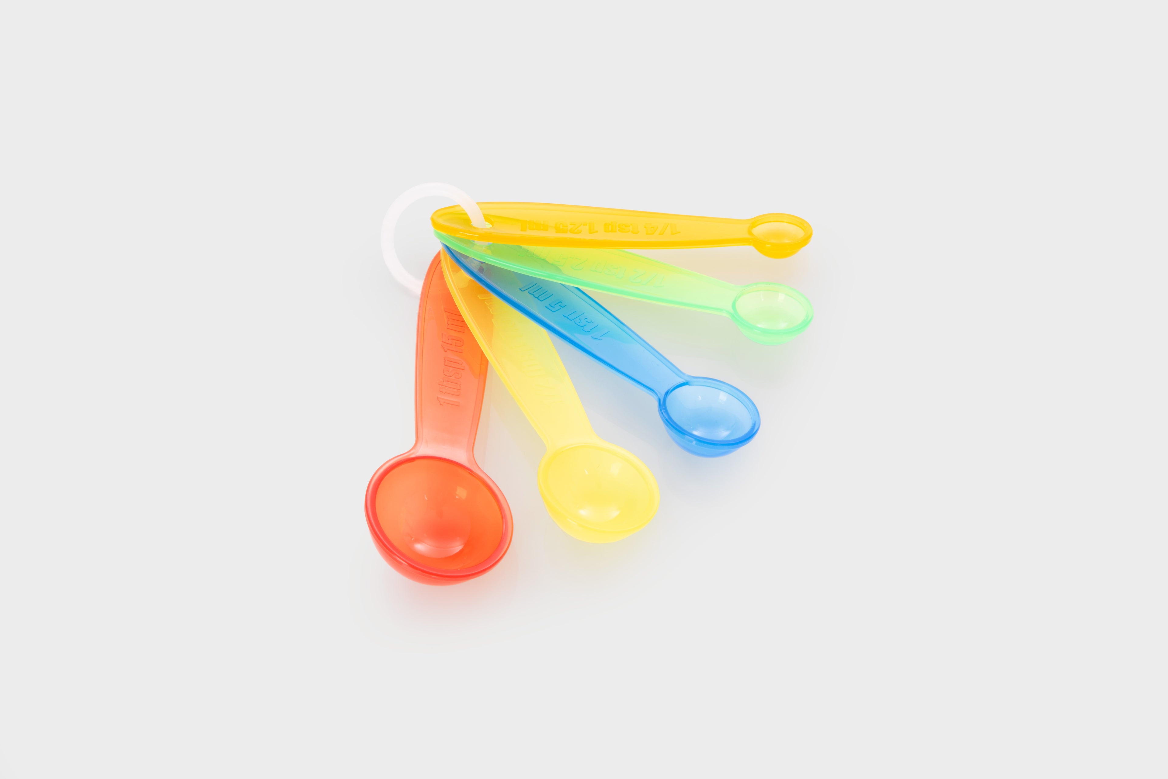 Translucent measuring spoon set, five nested colorful scoops with looped handles.