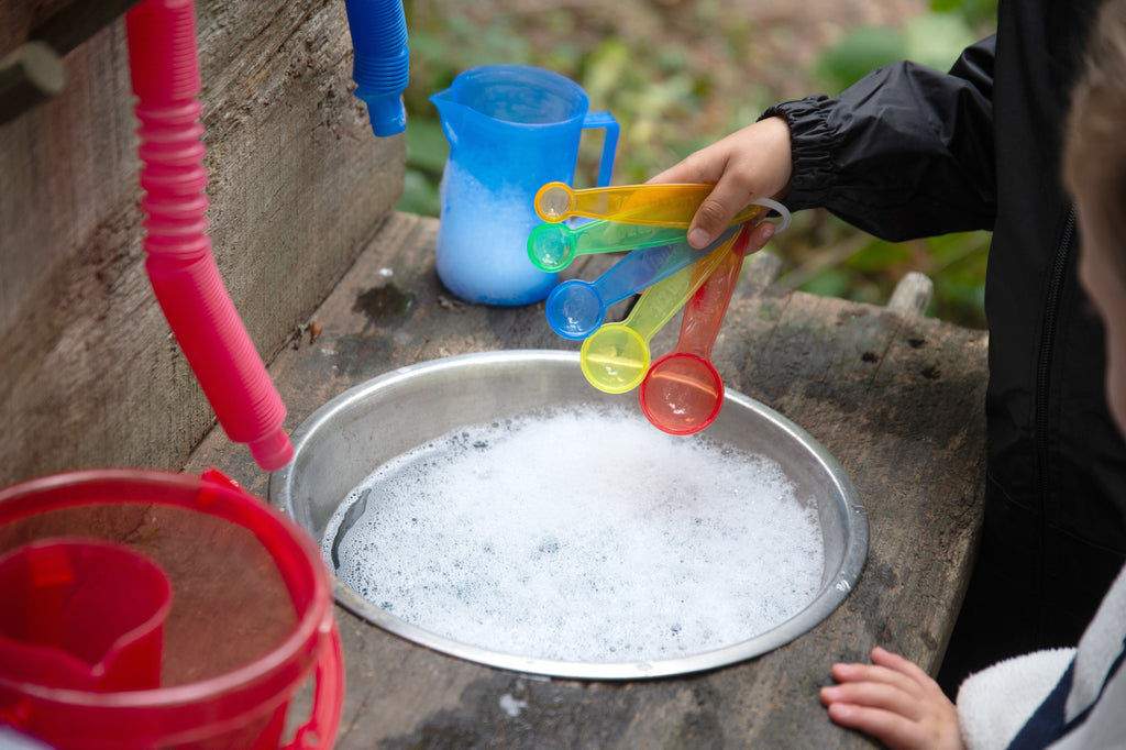 Translucent measuring spoons in use, rainbow scoops held over a metal tray.