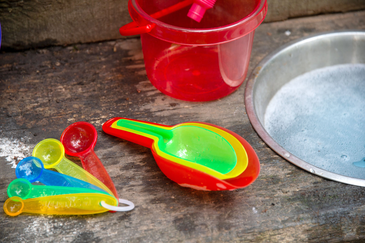 Translucent measuring spoon set with green and yellow scoops on a tabletop.