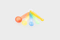 Translucent measuring spoon set with five rainbow-colored scoops and handles.