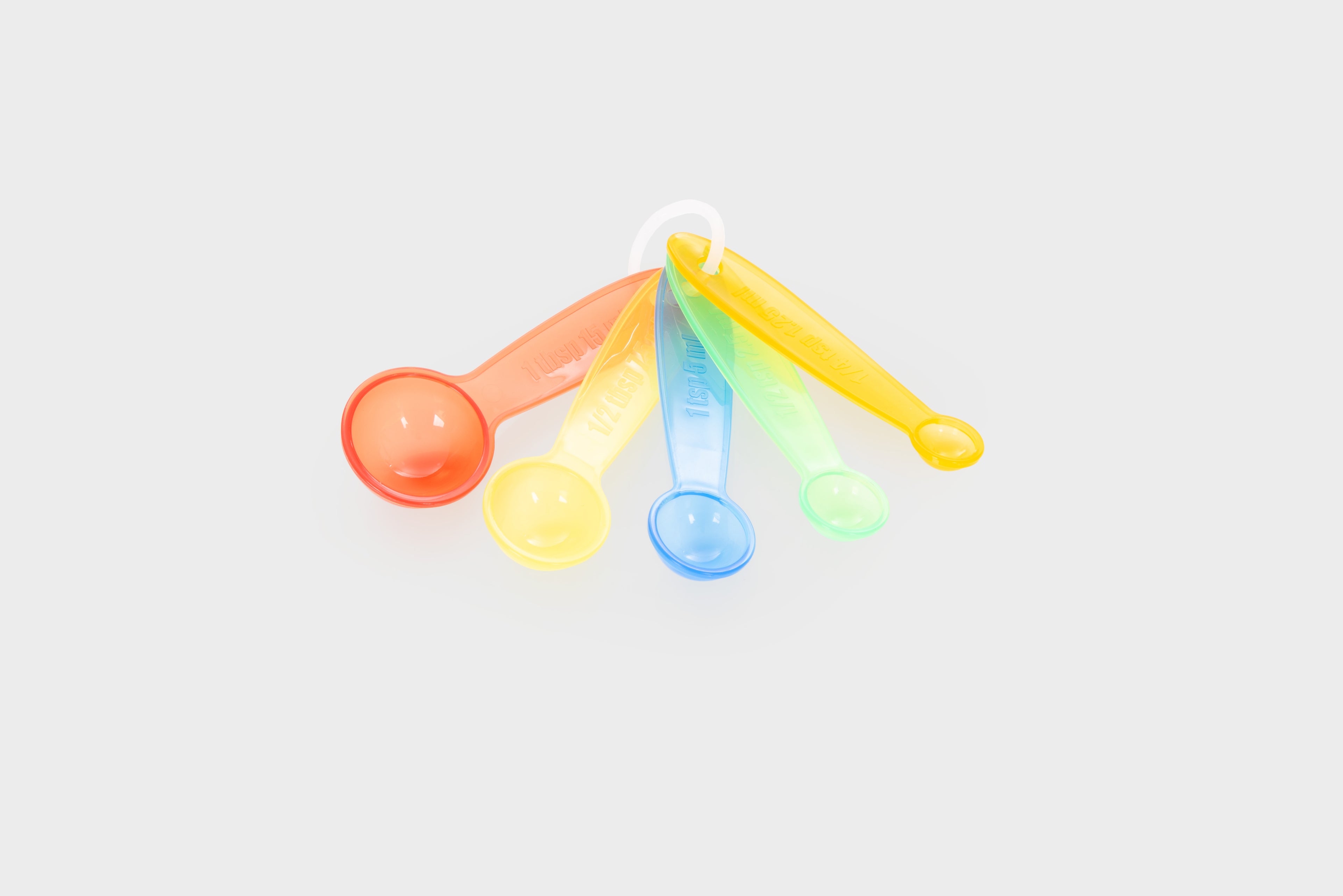 Translucent measuring spoon set with five rainbow-colored scoops and handles.
