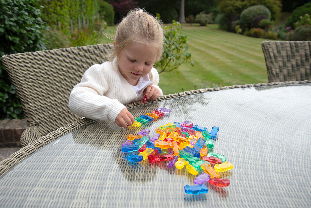Translucent toy cars on a quilted cushion while a child plays