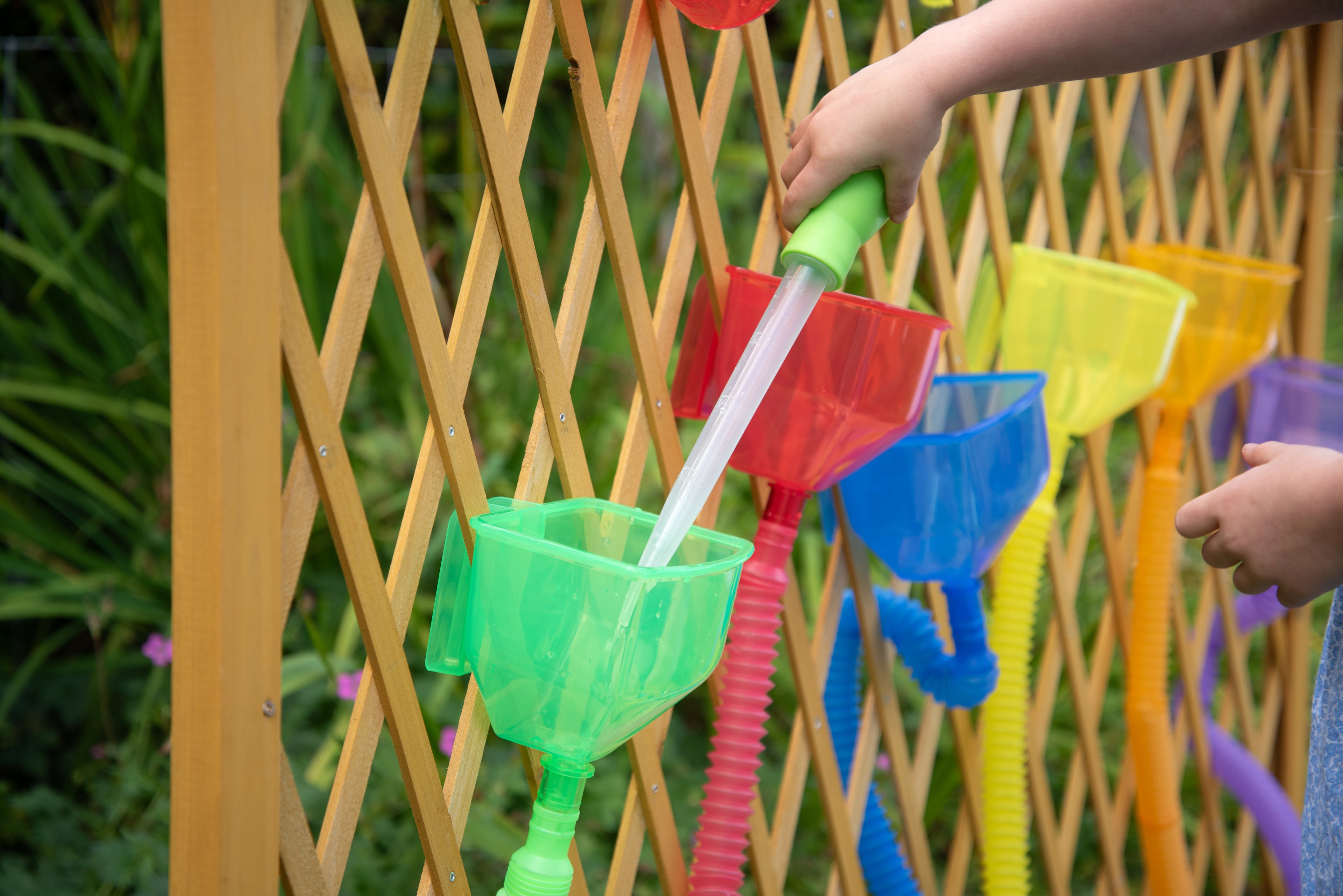 Translucent color funnel set with green and red funnels clipped on a wooden fence