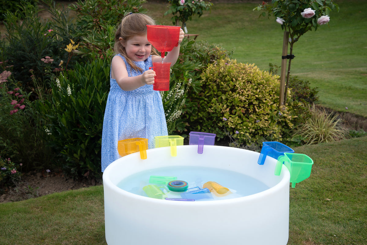 Translucent color funnel set: child holds a red funnel over a tub of colorful pieces