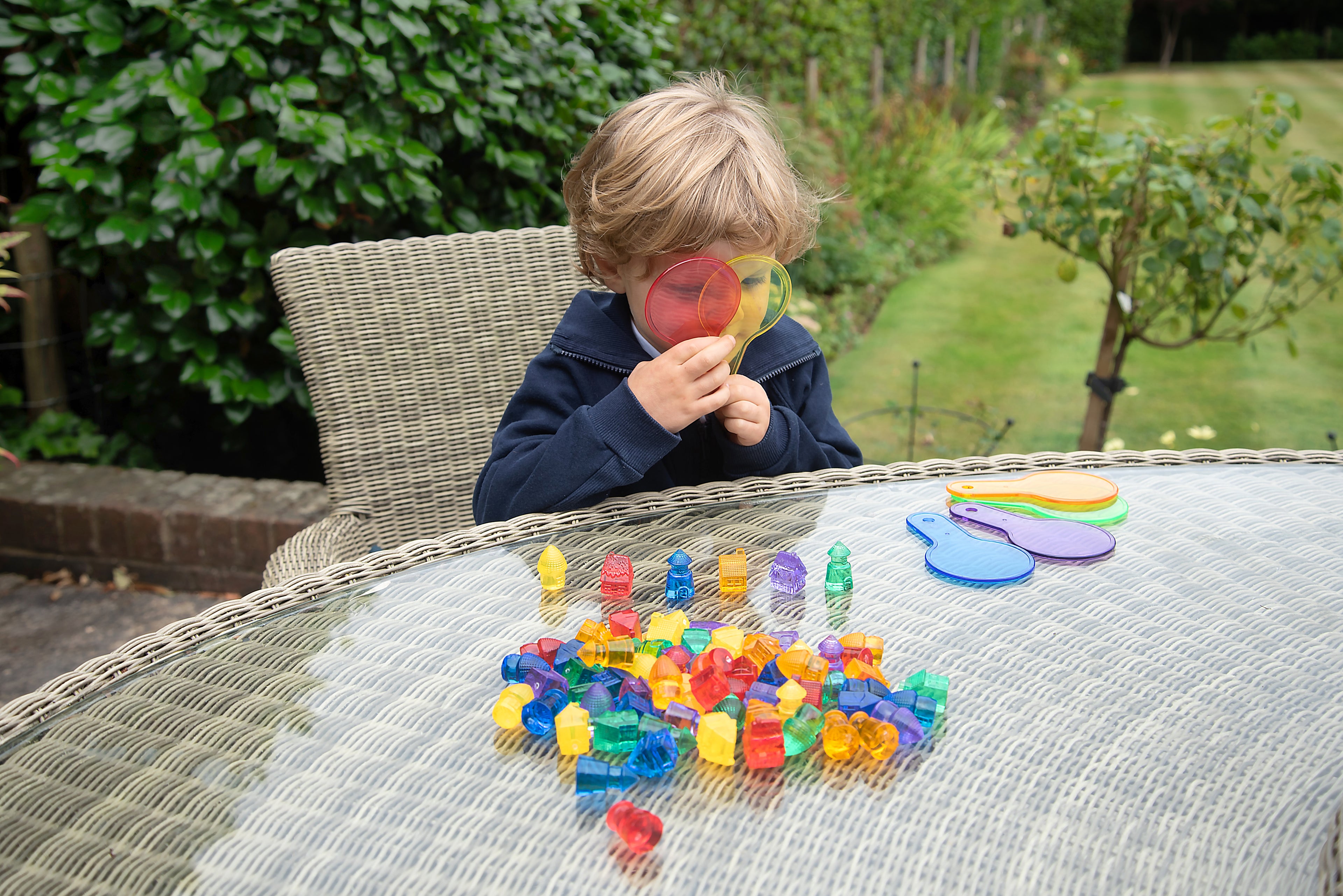 Child holding a translucent colored toy piece while playing with toy houses