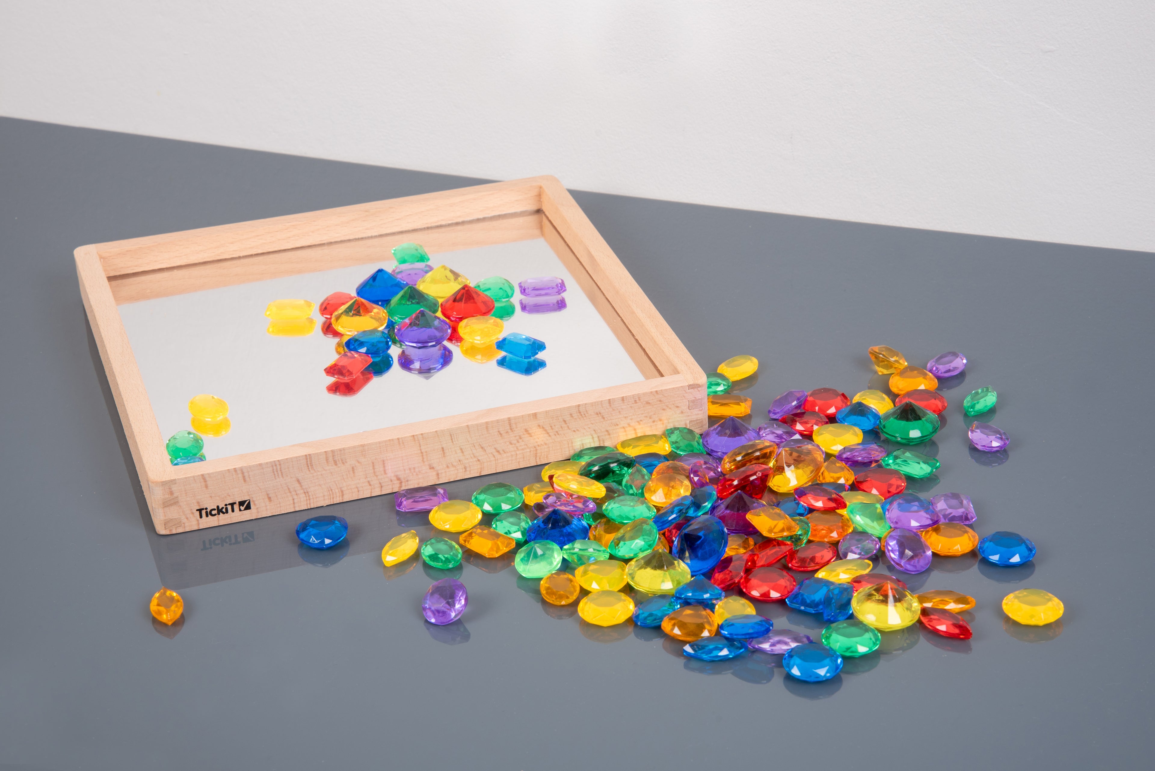 Wood tray of translucent colored jewel gems with mixed multicolor pieces