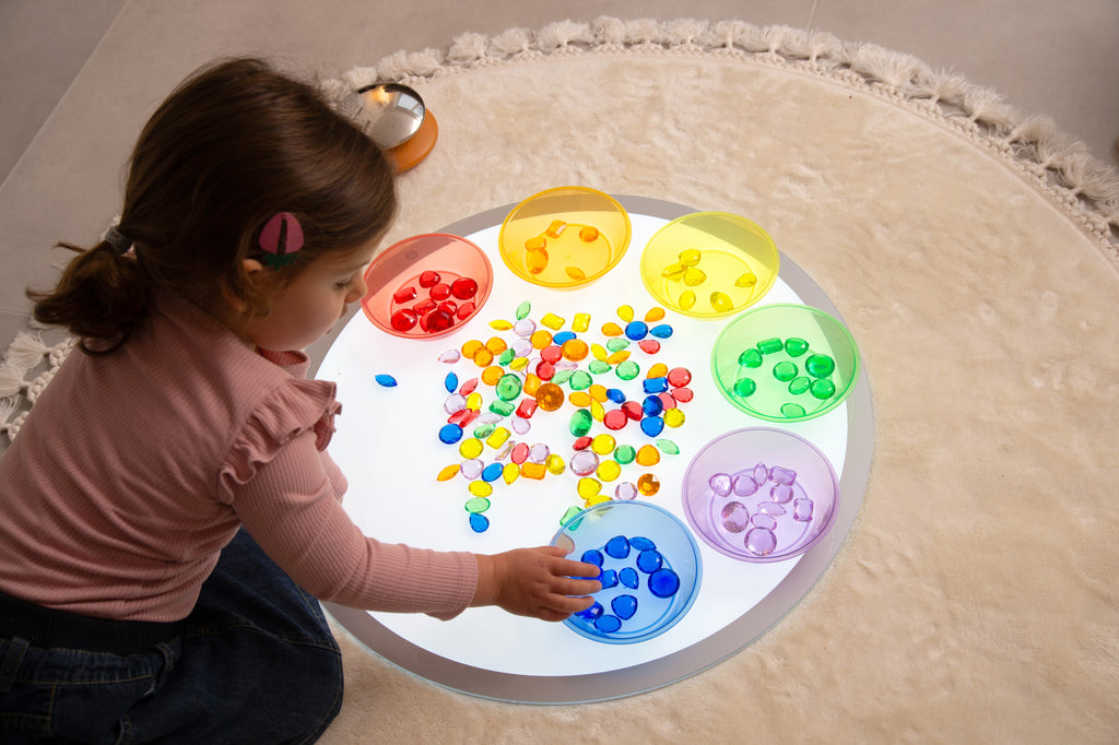 Translucent jewel gems in round divided tray with red, blue, green, yellow pieces