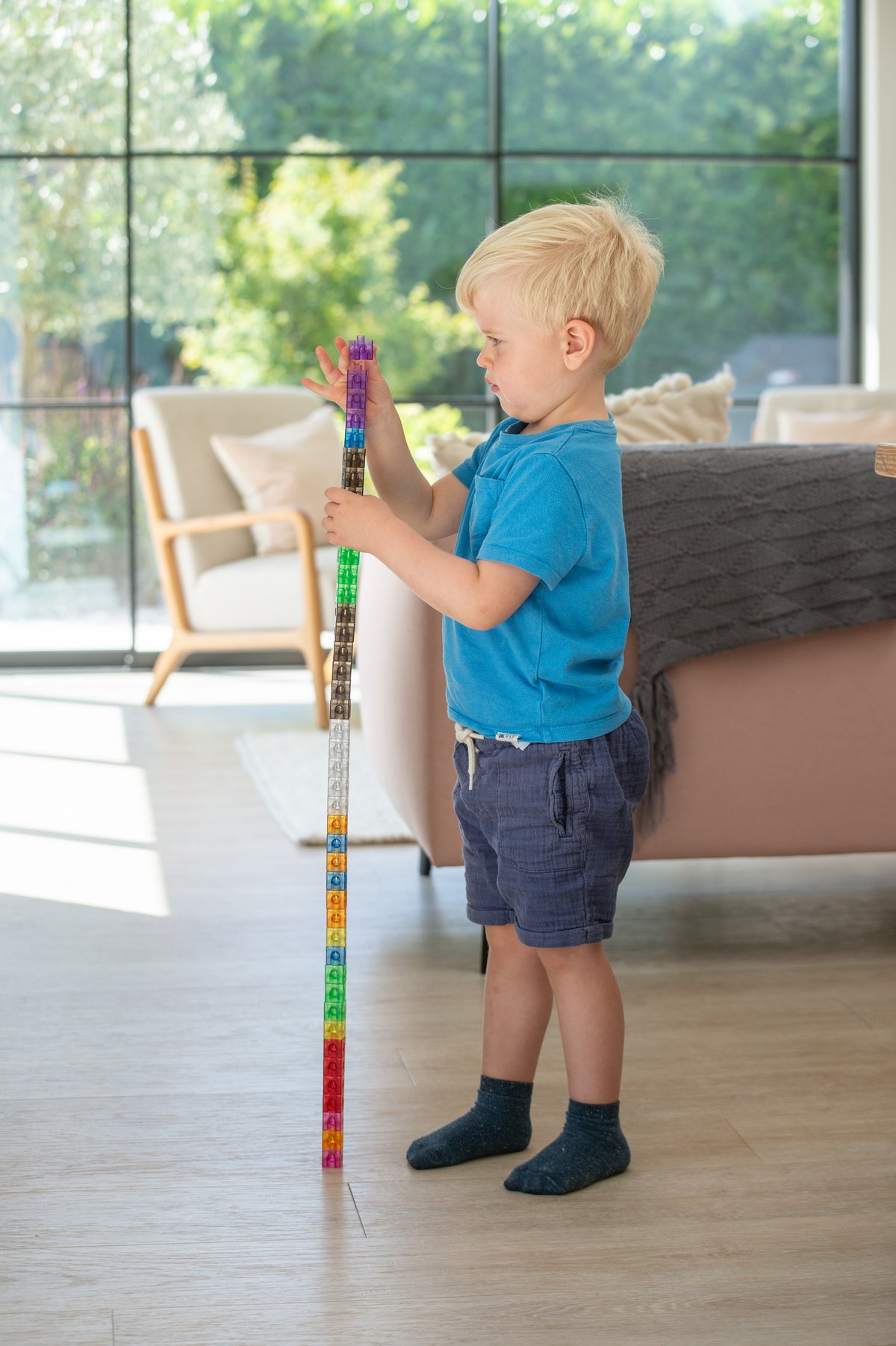 Child holding tall translucent linking cube stack, multicolor cubes on a rod