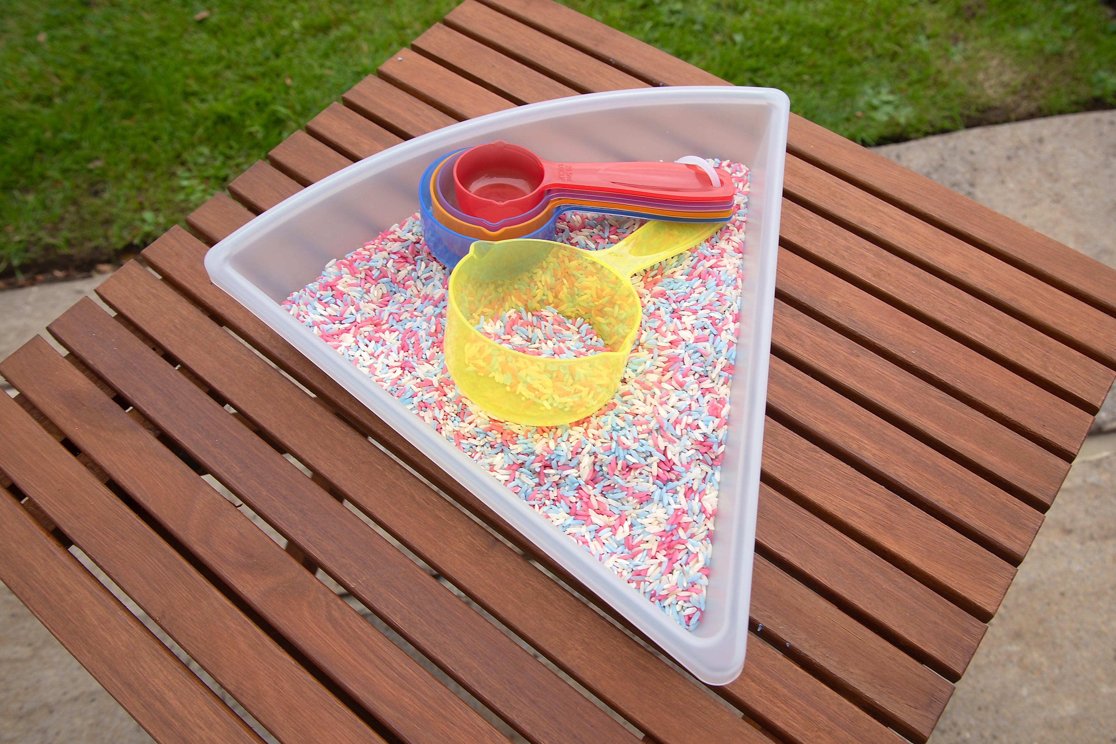 Translucent measuring cups in a tray with sprinkles, yellow round bowl and red handle