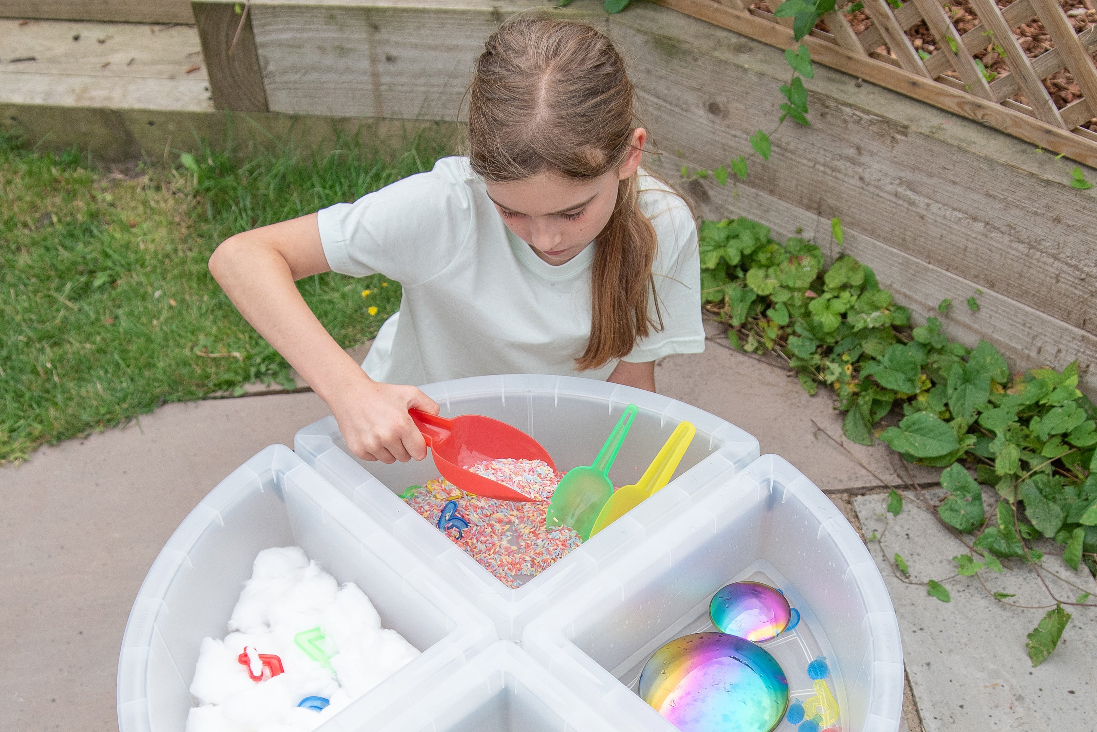 Translucent nesting scoops with red and multicolor scoops in a plastic bin