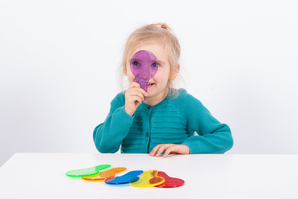 Translucent color paddle toy with curved handle; child holds purple paddle near face.