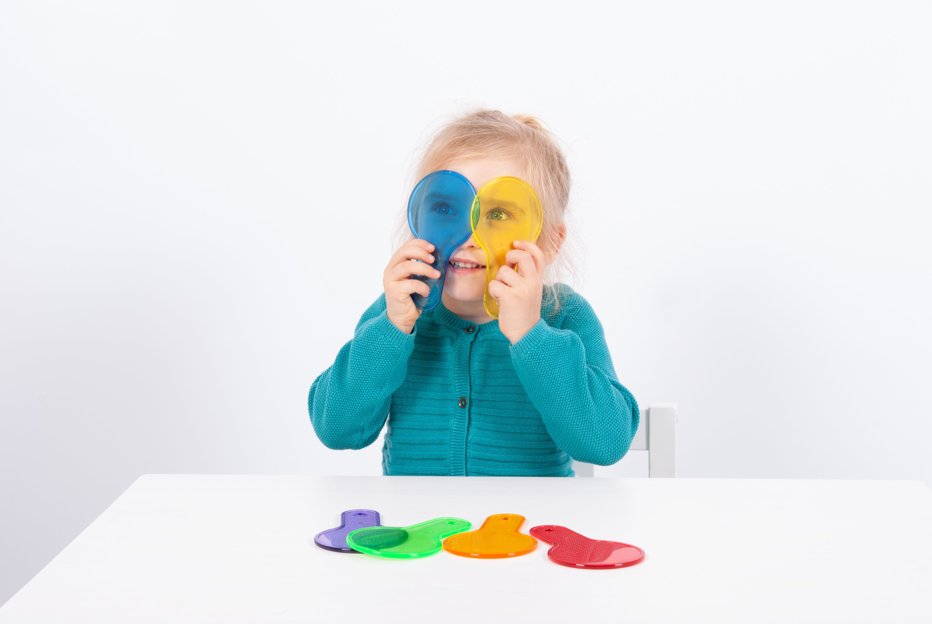 Translucent color paddle toys with handles; child holds blue and yellow paddles in front of face.