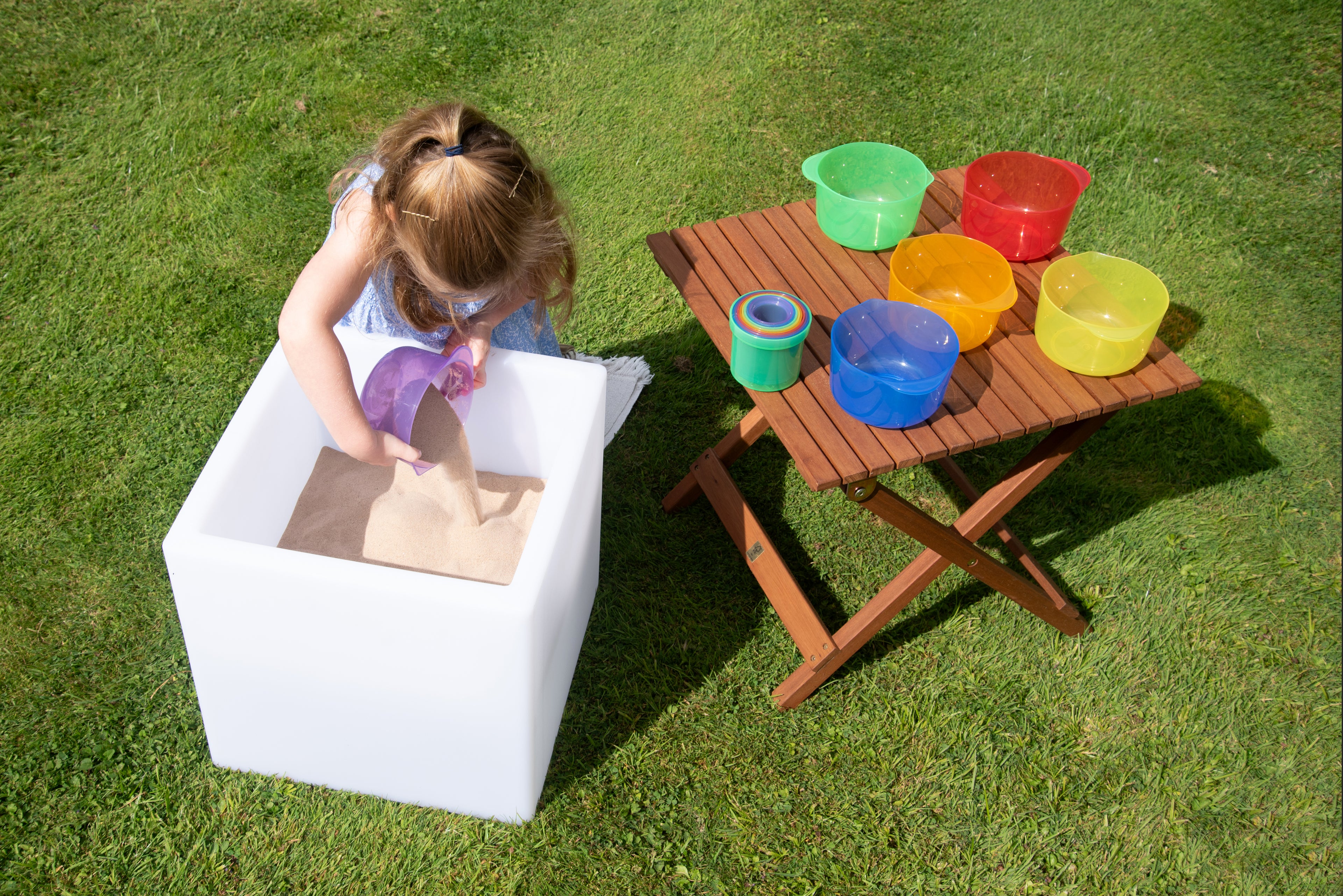 Translucent pouring bowls on wooden table: green, red, orange, blue, and yellow