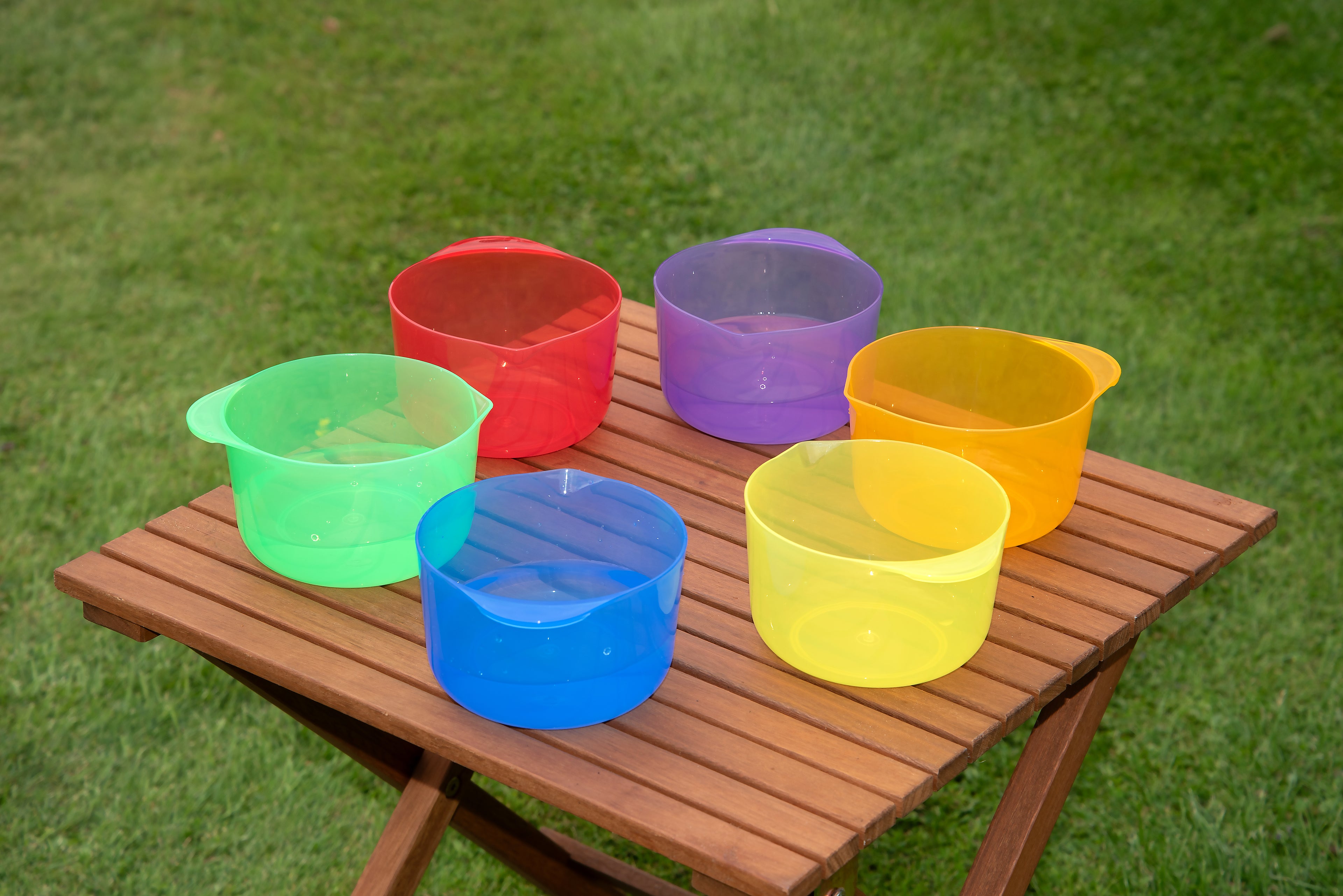Translucent pouring bowls assortment on wooden tray: red, green, blue, yellow, purple