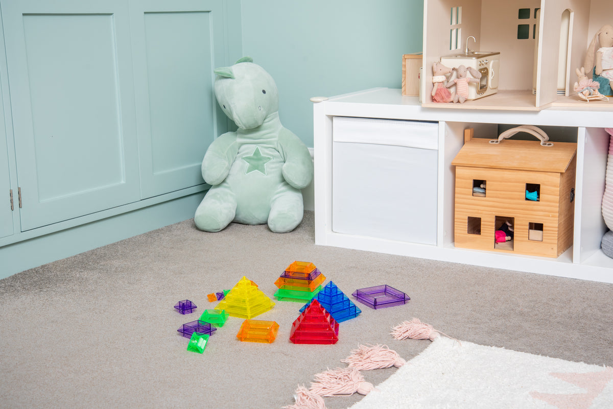 Translucent pyramid builder pieces scattered on carpet in rainbow colors