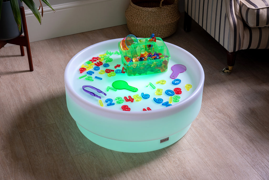 Translucent green bin with colorful letter-number pieces on a round light base
