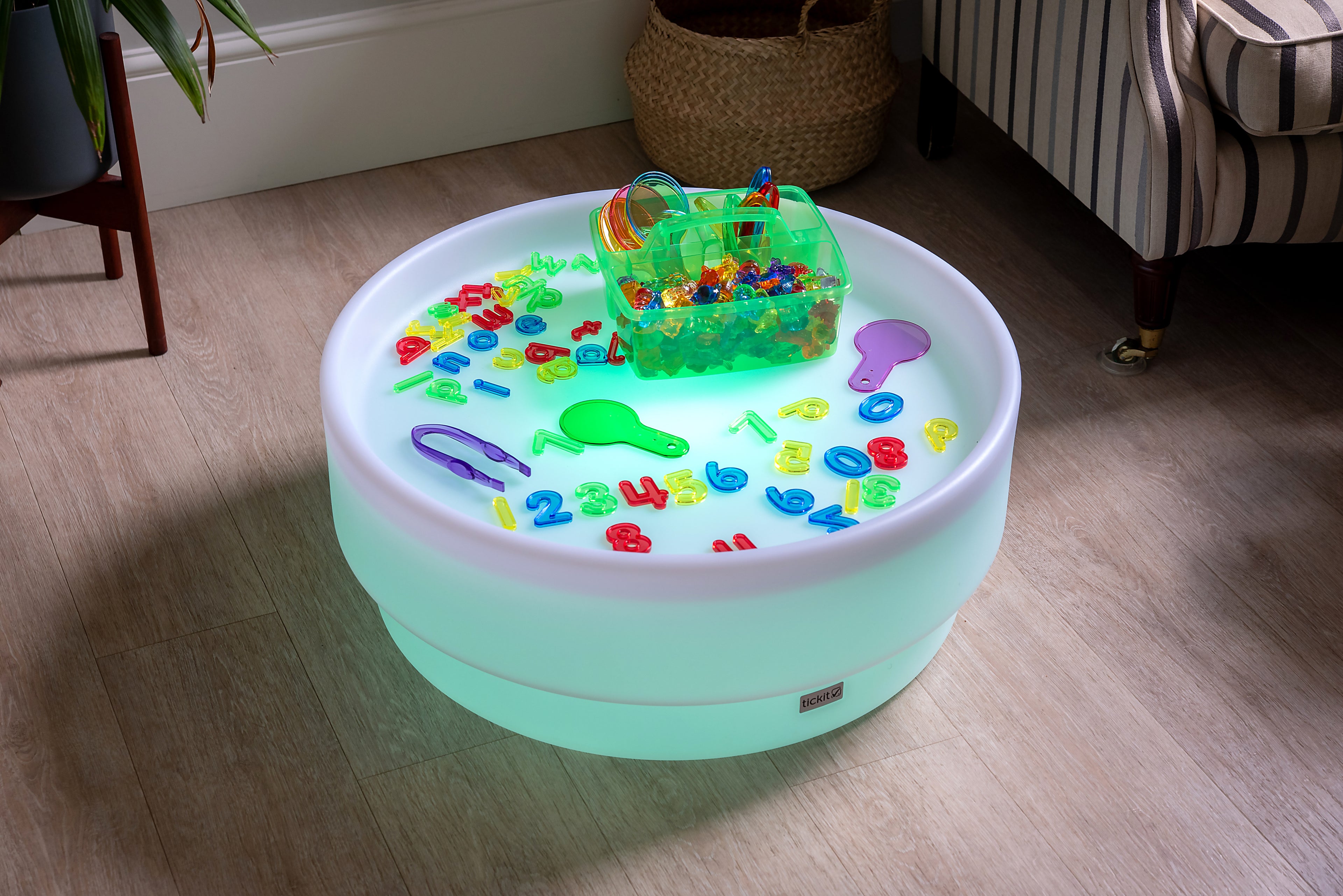 Translucent green bin with colorful letter-number pieces on a round light base