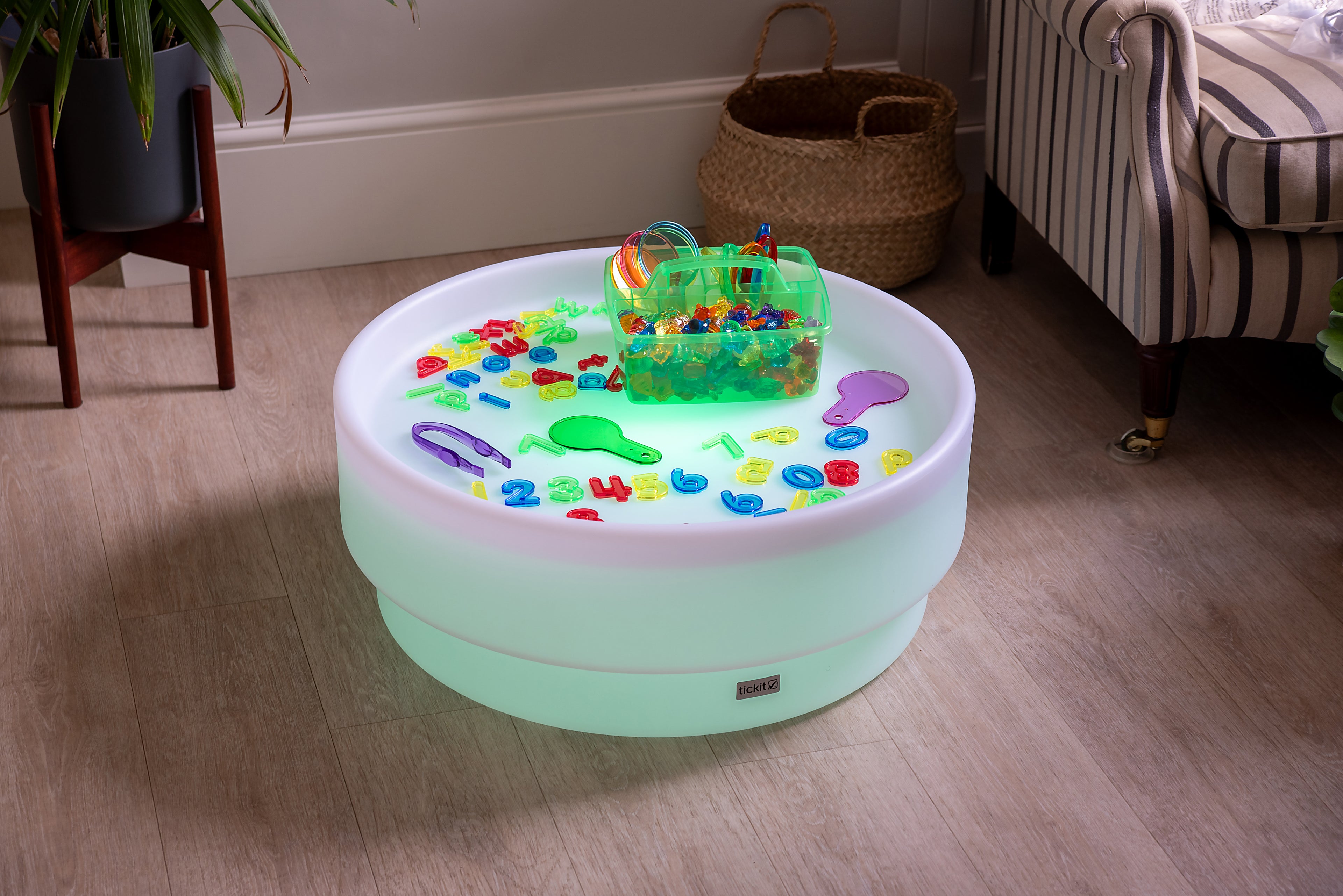 Translucent green bin and colorful number-letter pieces on a round light base