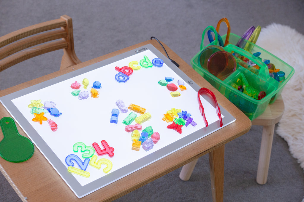 Colorful number and letter pieces on a tablet with green translucent bin