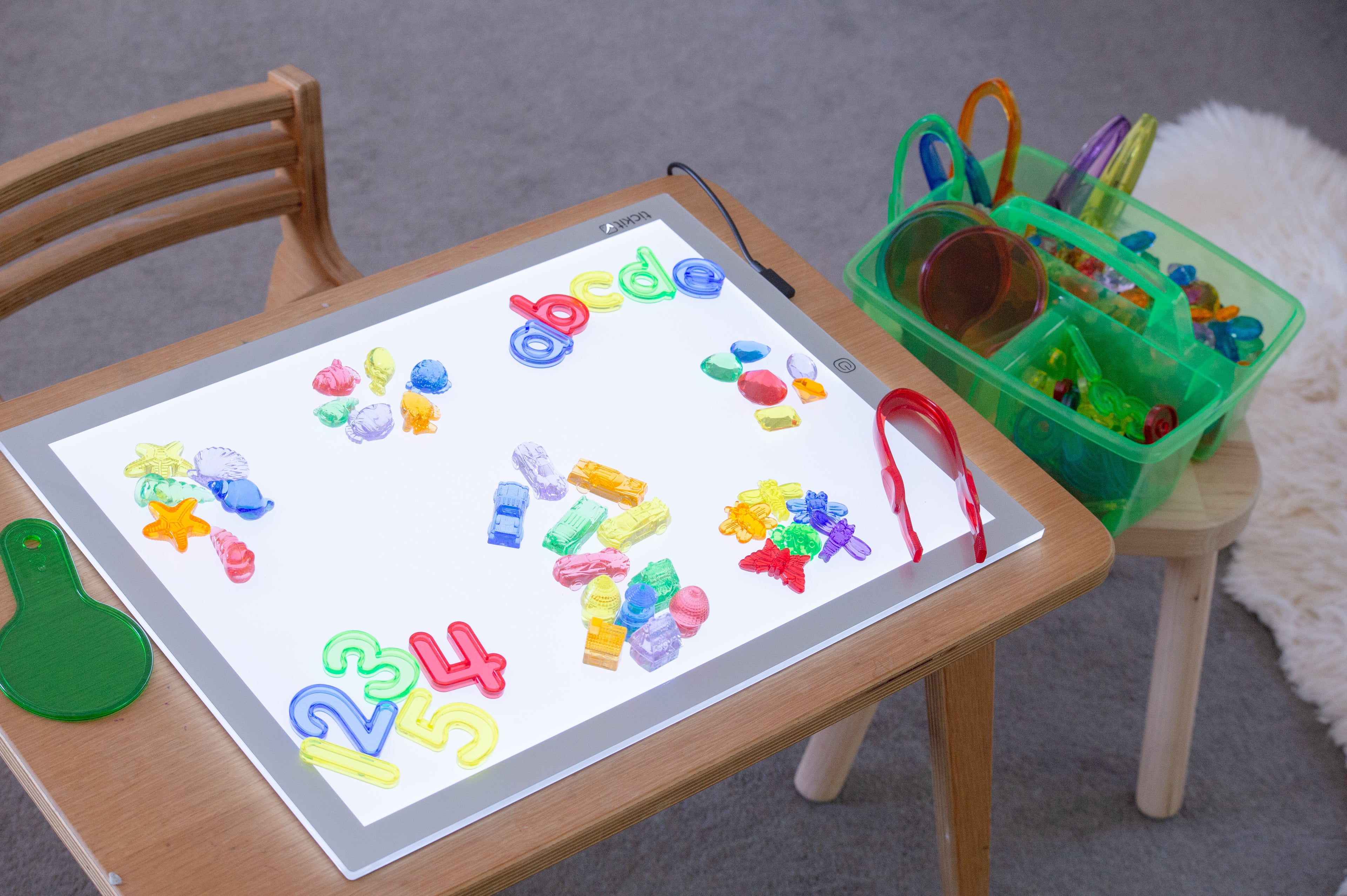 Colorful number and letter pieces on a tablet with green translucent bin