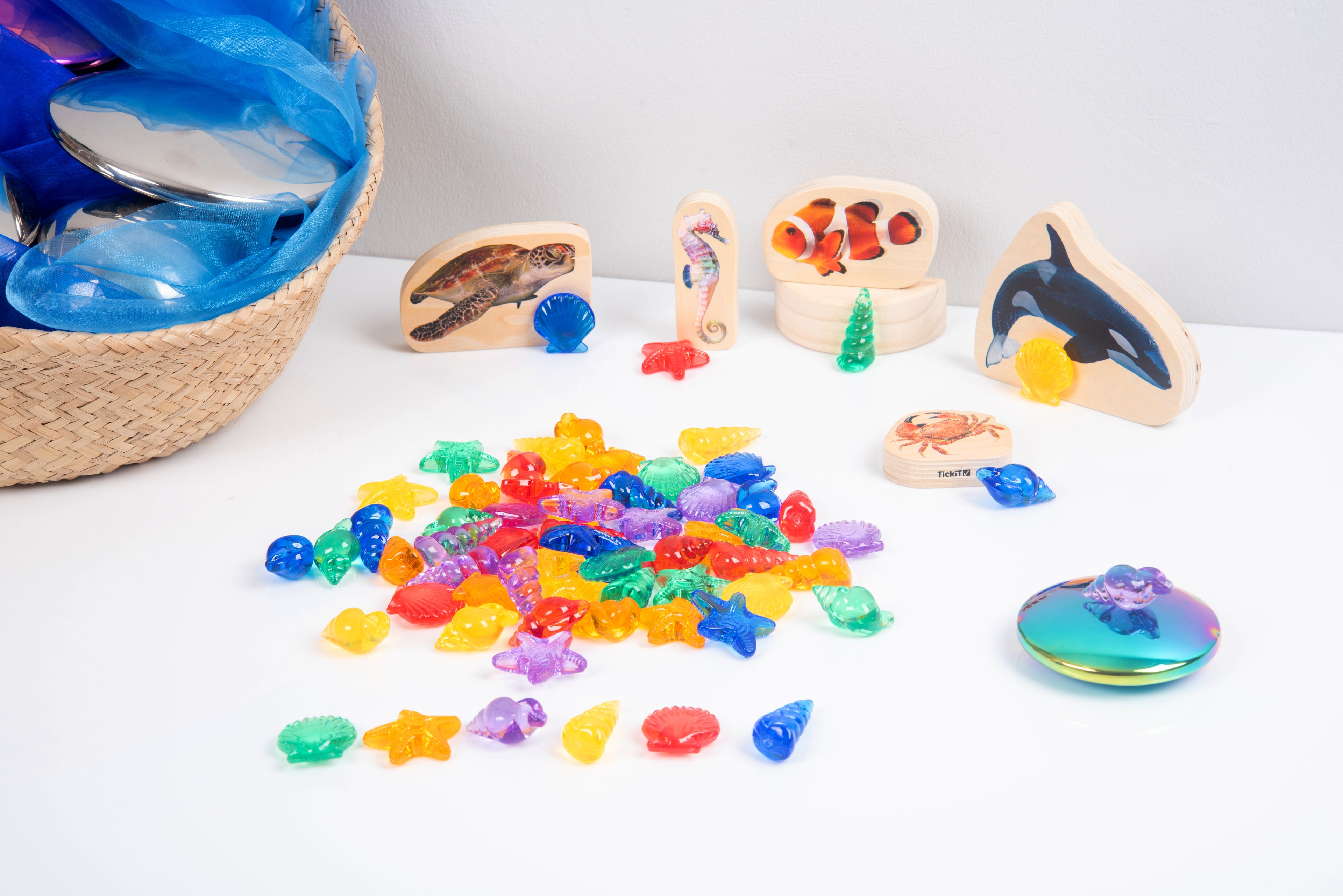 Translucent color shells with small sea-animal toys and rainbow mirror disc on table