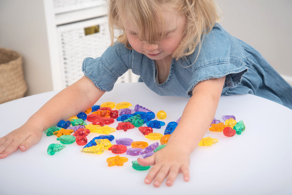Translucent color shells set as child reaches through scattered colorful shell shapes