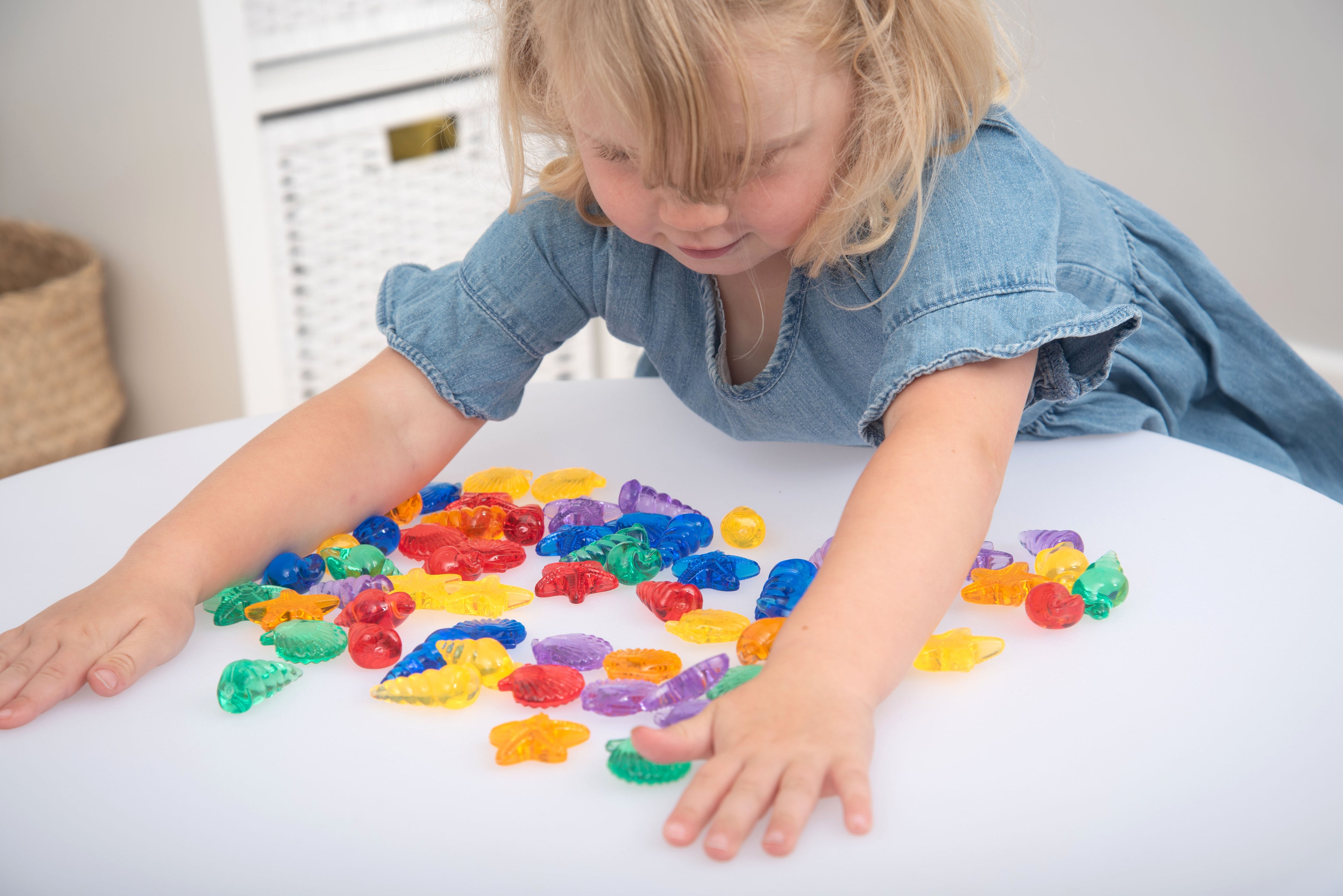 Translucent color shells set as child reaches through scattered colorful shell shapes