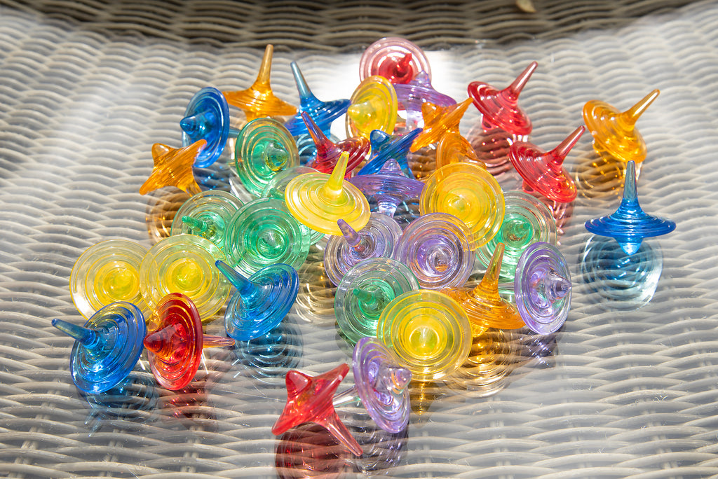 Close-up of translucent multicolor swirl spinners piled on a textured outdoor surface