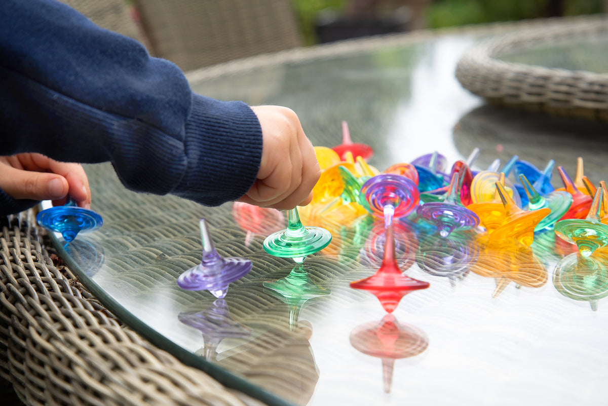 Hand placing translucent swirl spinners on a glass outdoor table