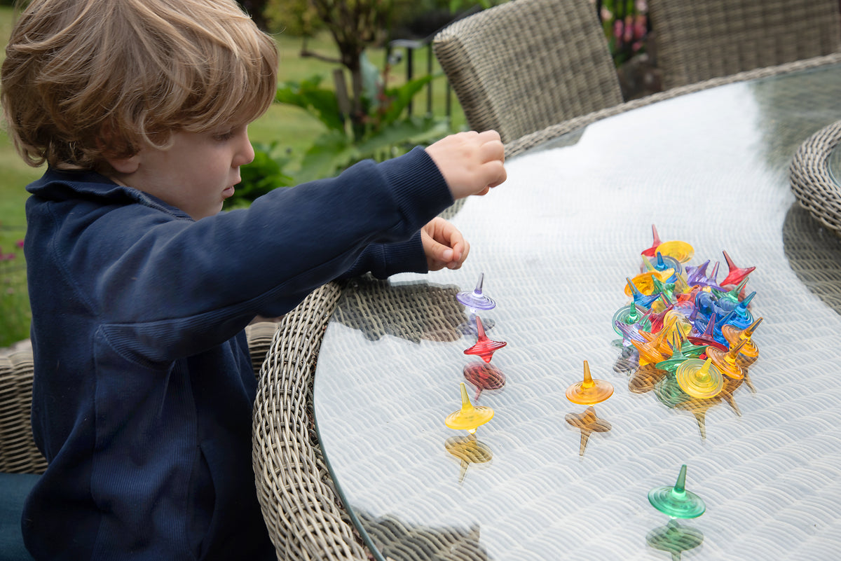 Child arranging translucent color spinners on a table covered with multiple swirl tops